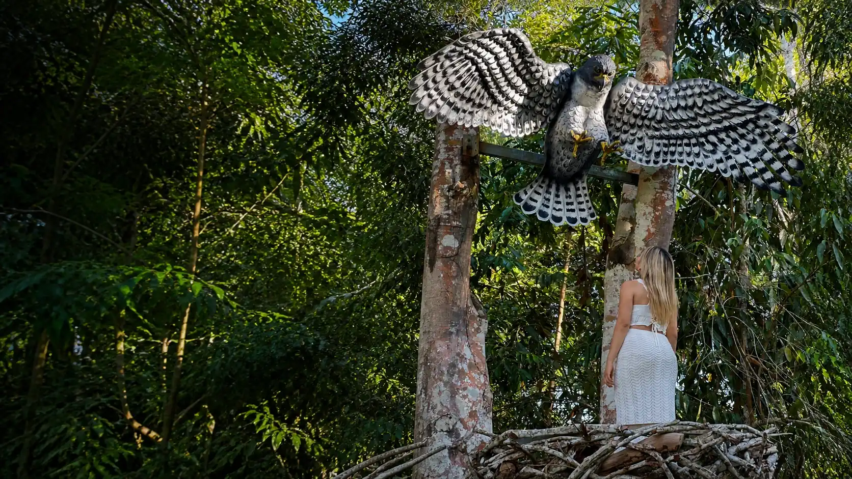 Visitante junto a la escultura de un águila de alas abiertas